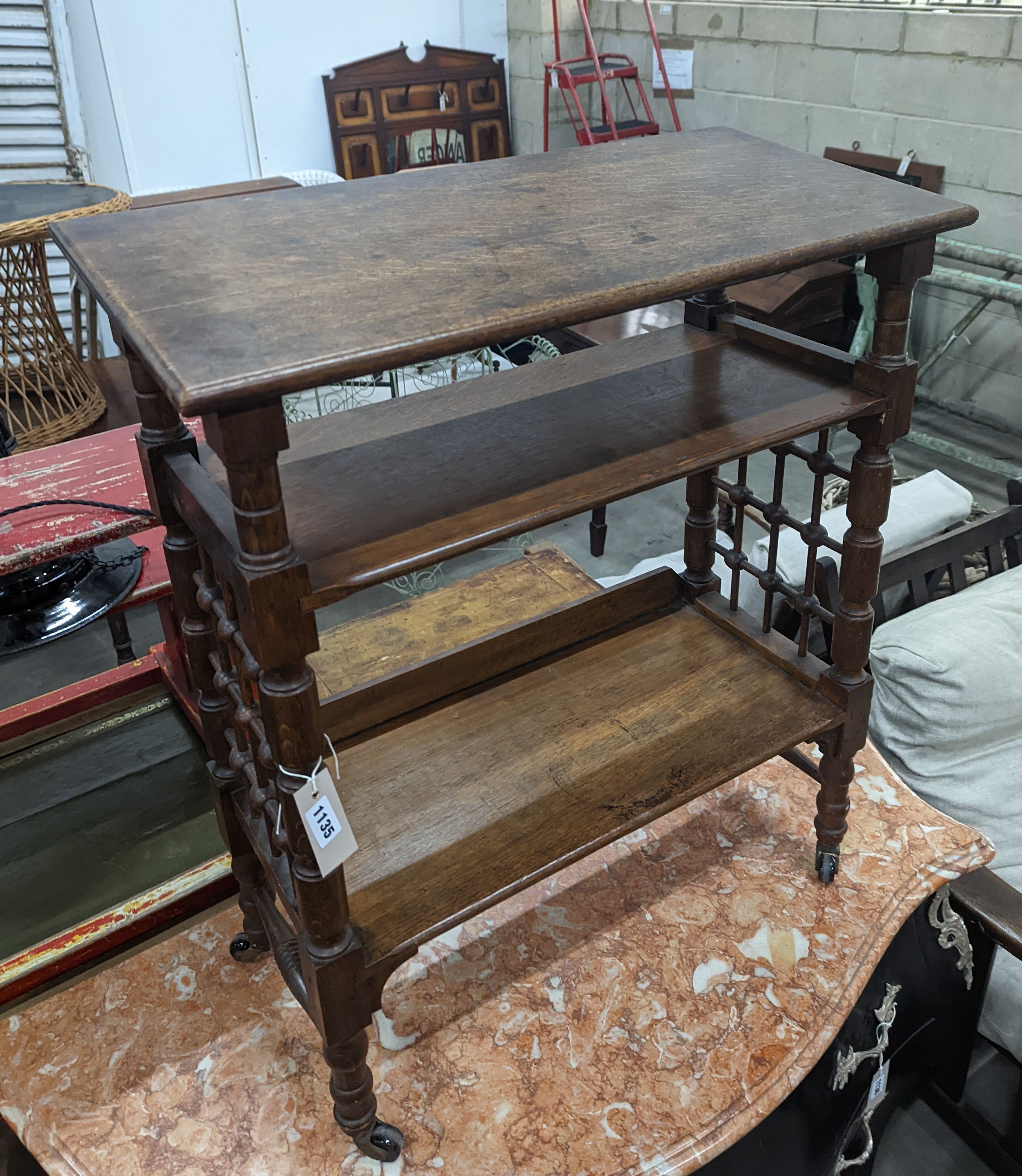 A late 19th century Continental oak three tier Liberty style table with slant top, width 70cm, depth 29cm, height 78cm